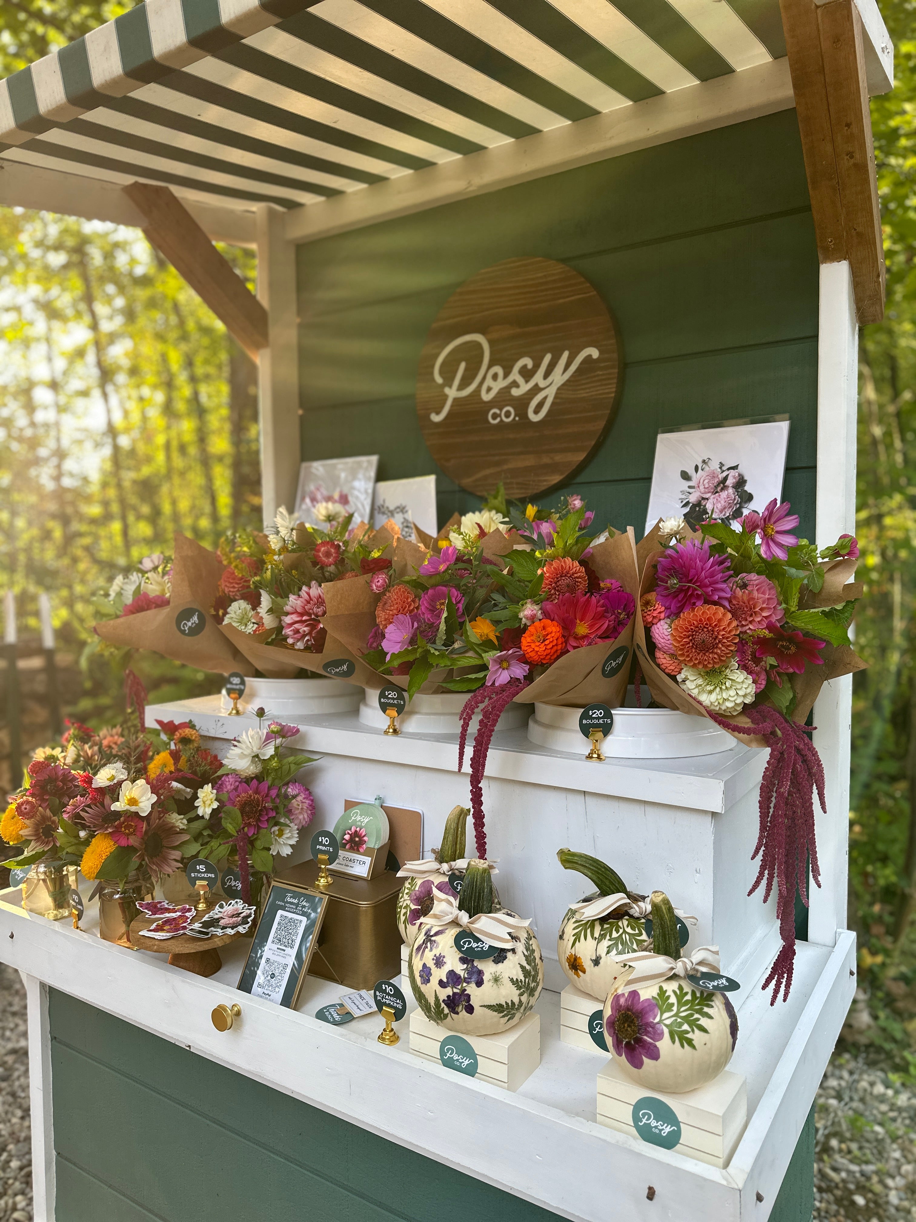 A photo of a flower stand with bouquets and pumpkins